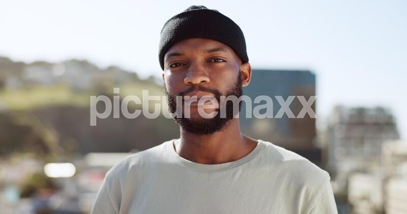Face, confident and city with an edgy black man outdoor in an urban town for fashion or street style. Portrait, cityscape and lifestyle with a young African American male outside on a summer day.